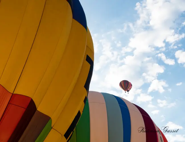 Colorful hot air balloons ascending into the sky at the Balloon Fest in Provo, Utah, with a crowd of spectators enjoying the vibrant spectacle.