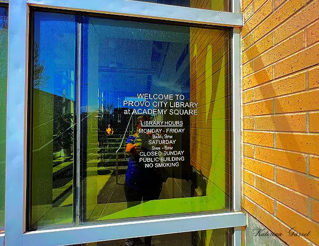 Photo showing the library hours of Provo City Library at Academy Square engraved in glass...