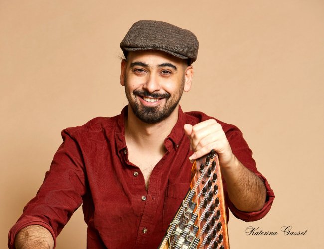 Firas Zreik performing live at BYU, passionately playing the qanun with a captivating stage presence, set against a vibrant concert hall backdrop.